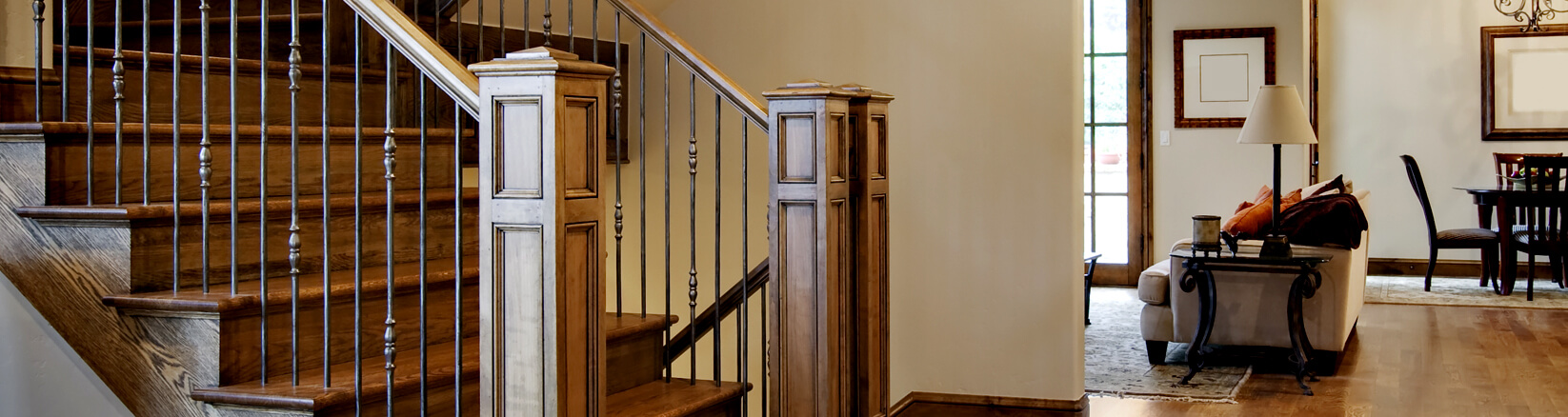 a narrow image of brown floors of a stairwell, landing and bannister